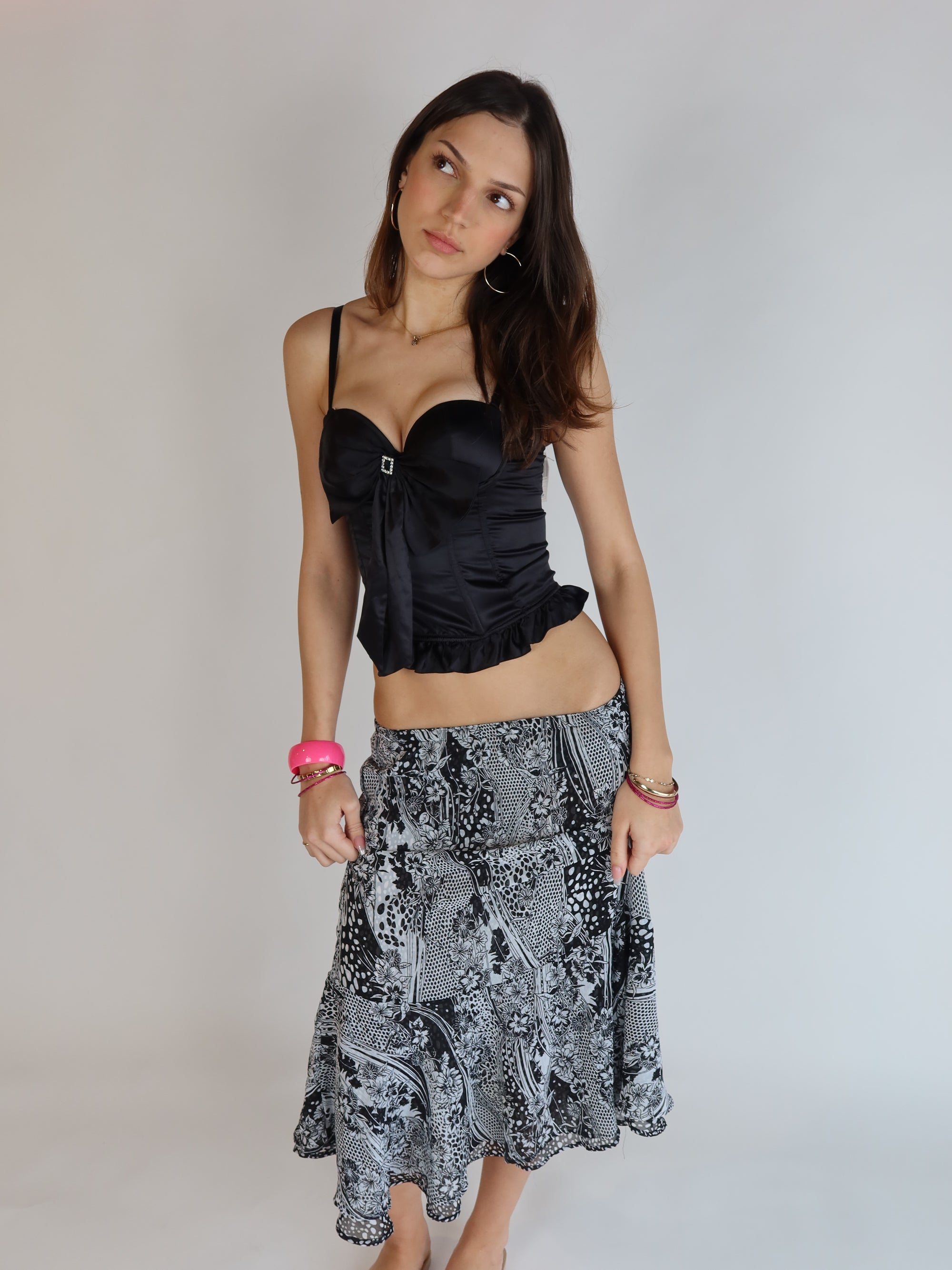Vintage Y2K black satin corset top with oversized bow front, rhinestone buckle detail, ruffle hem, adjustable straps, and full hook-and-eye back closure