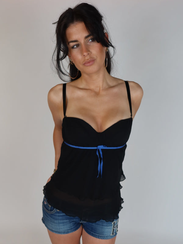 Vintage Y2K black sheer babydoll cami top featuring a sweetheart neckline, blue ribbon empire waist tie, adjustable straps, and flowy chiffon overlay styled with denim shorts.