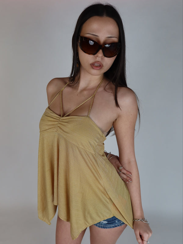 Vintage Y2K mustard yellow babydoll cami top featuring a ruched sweetheart neckline, strappy halter-inspired detail, adjustable spaghetti straps, and a flowy handkerchief hem styled with denim shorts.