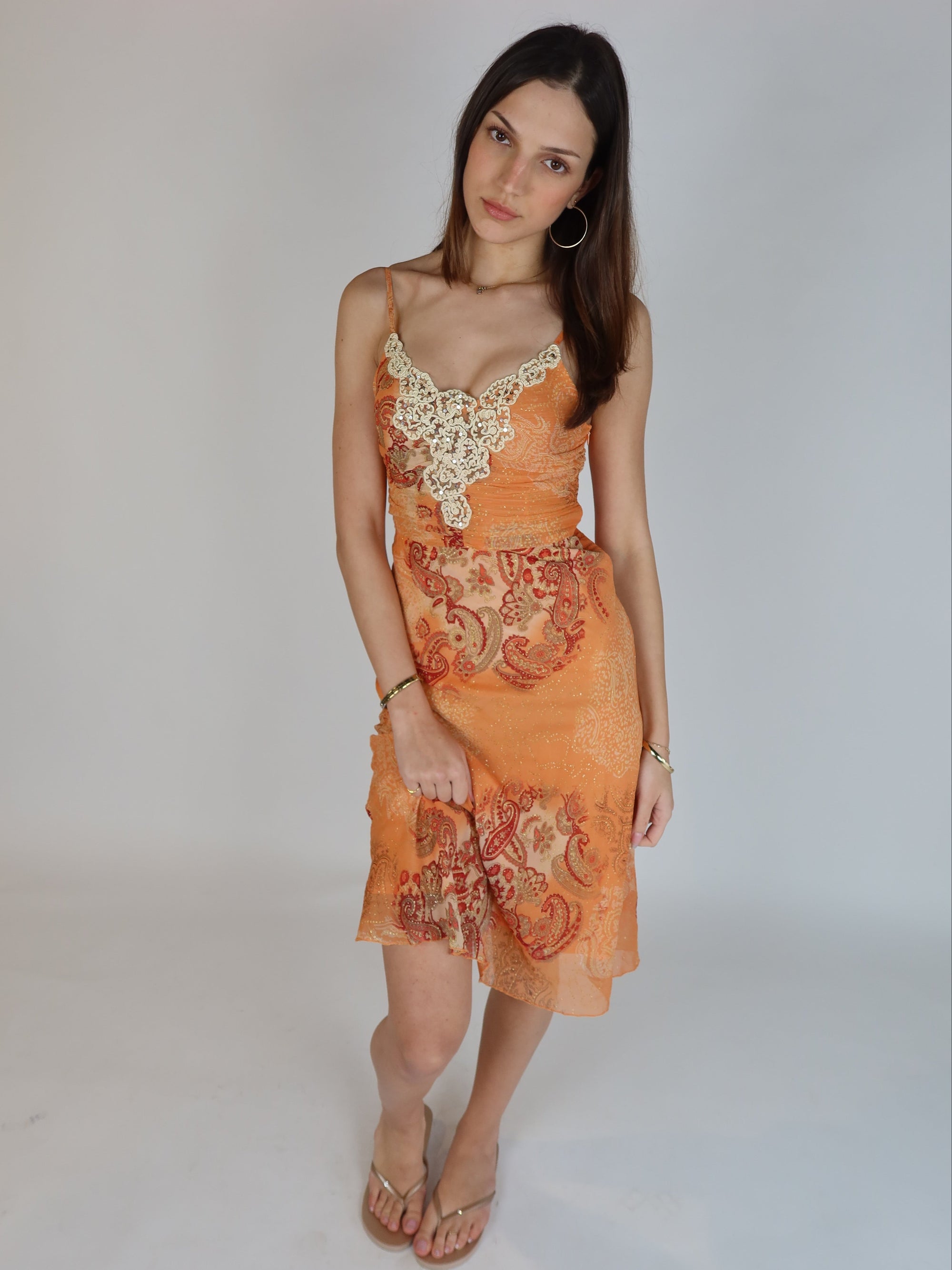 Vintage Y2K orange paisley slip dress with cream lace appliqué neckline, spaghetti straps, subtle shimmer details, and midi-length silhouette.
