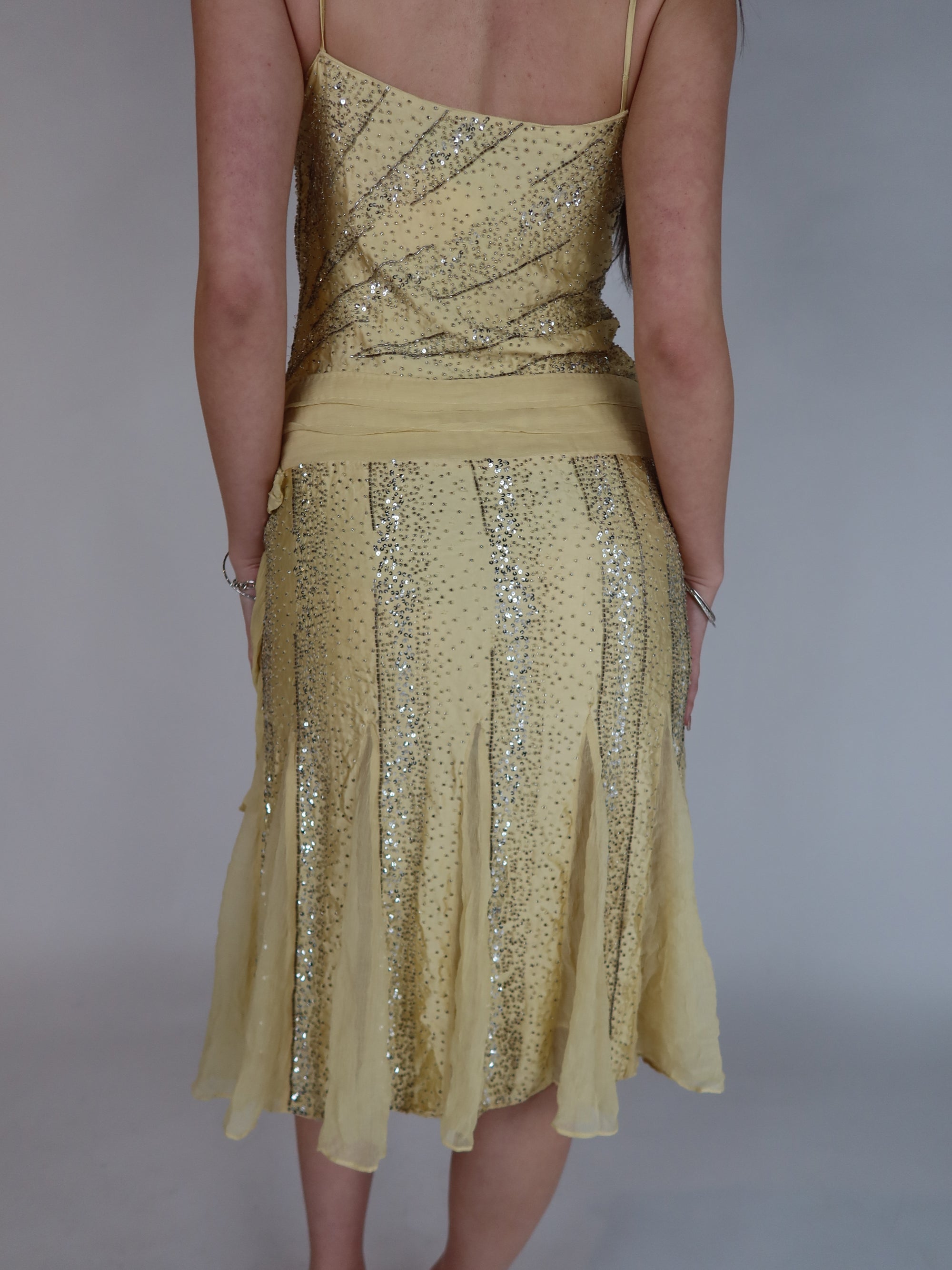 Vintage Y2K 100% silk beaded evening dress with intricate silver embellishments, spaghetti straps, matching waist tie, and handkerchief hem skirt.