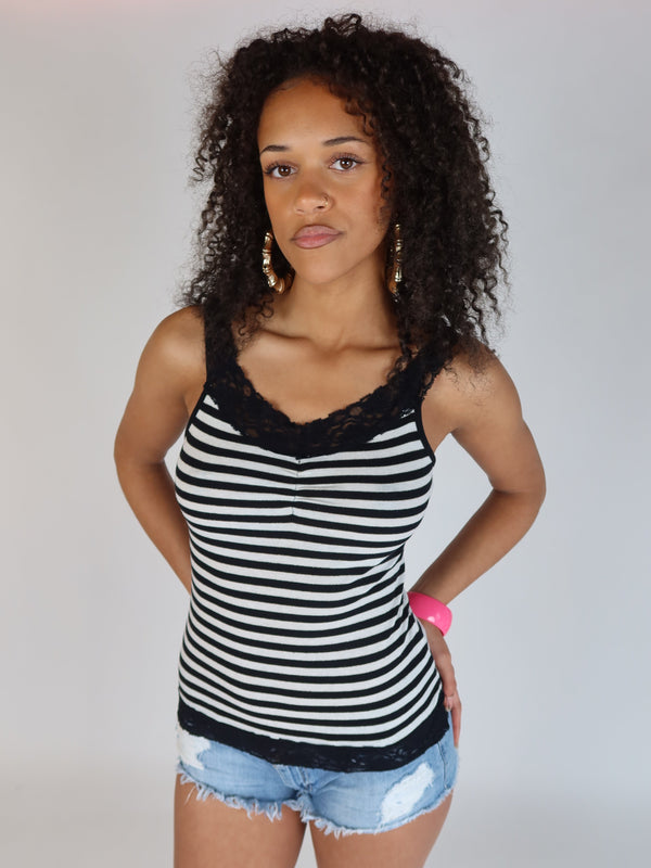 Vintage Y2K black and white striped tank top with black lace trim at the neckline and hem, shown on a model wearing light wash denim shorts.